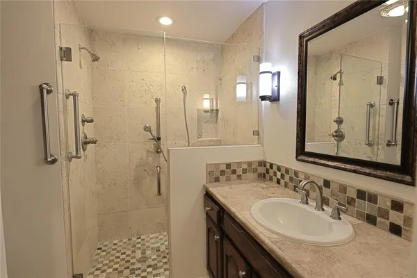 a bathroom with a granite countertop sink a mirror and shower