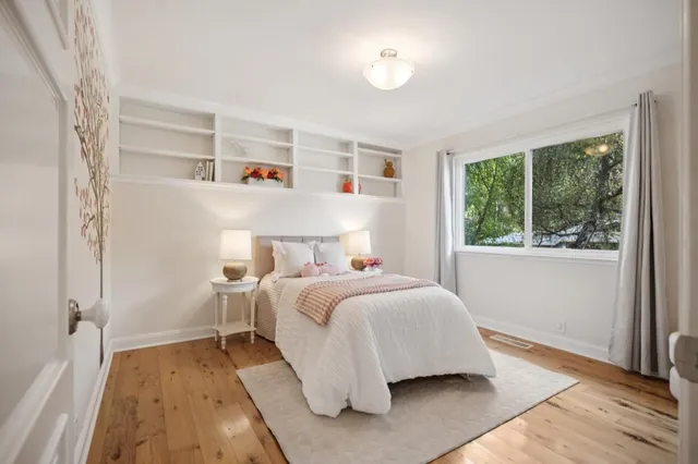 a bedroom with a bed and a large window with wooden floor