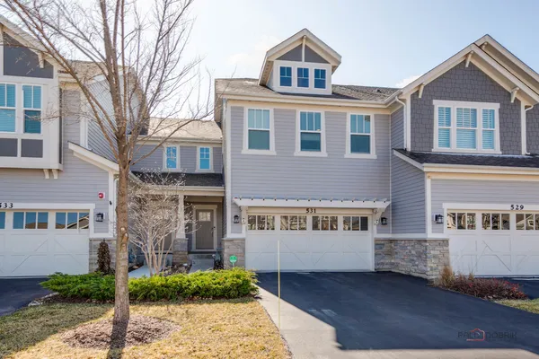 a front view of a house with a garden and trees