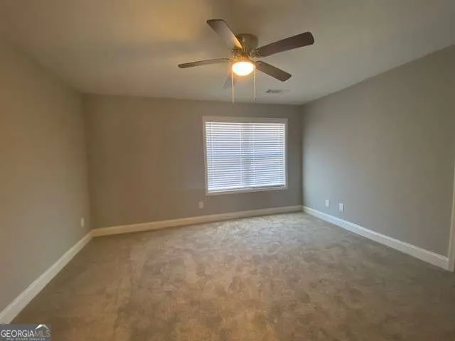 an empty room with windows and fan