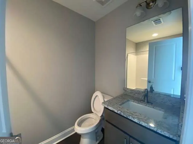 a bathroom with a granite countertop toilet sink and mirror