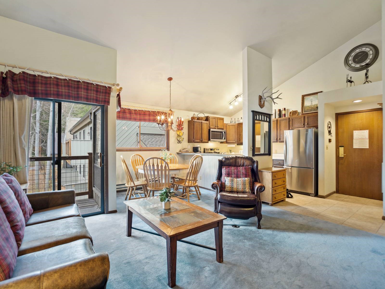 Living room with vaulted ceiling, a notable chandelier, and light tile patterned flooring