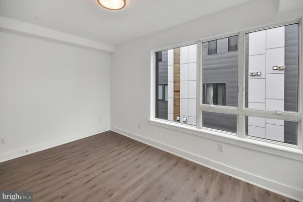 a view of an empty room with a window and wooden floor