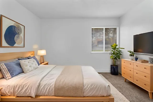 a bedroom with a bed and a flat tv screen on dresser