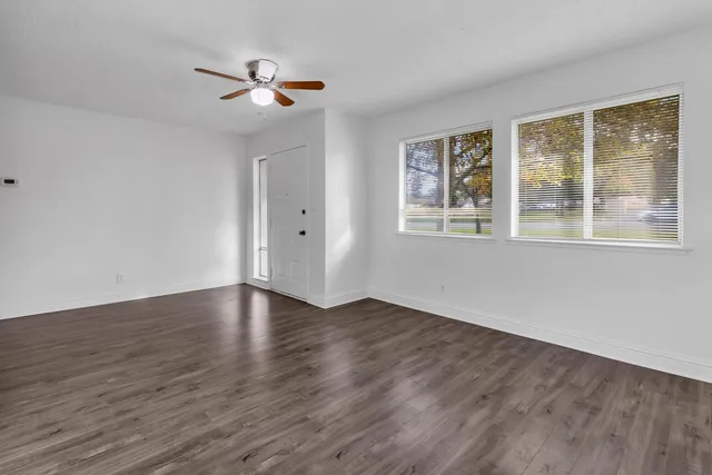 a view of an empty room with wooden floor and a window