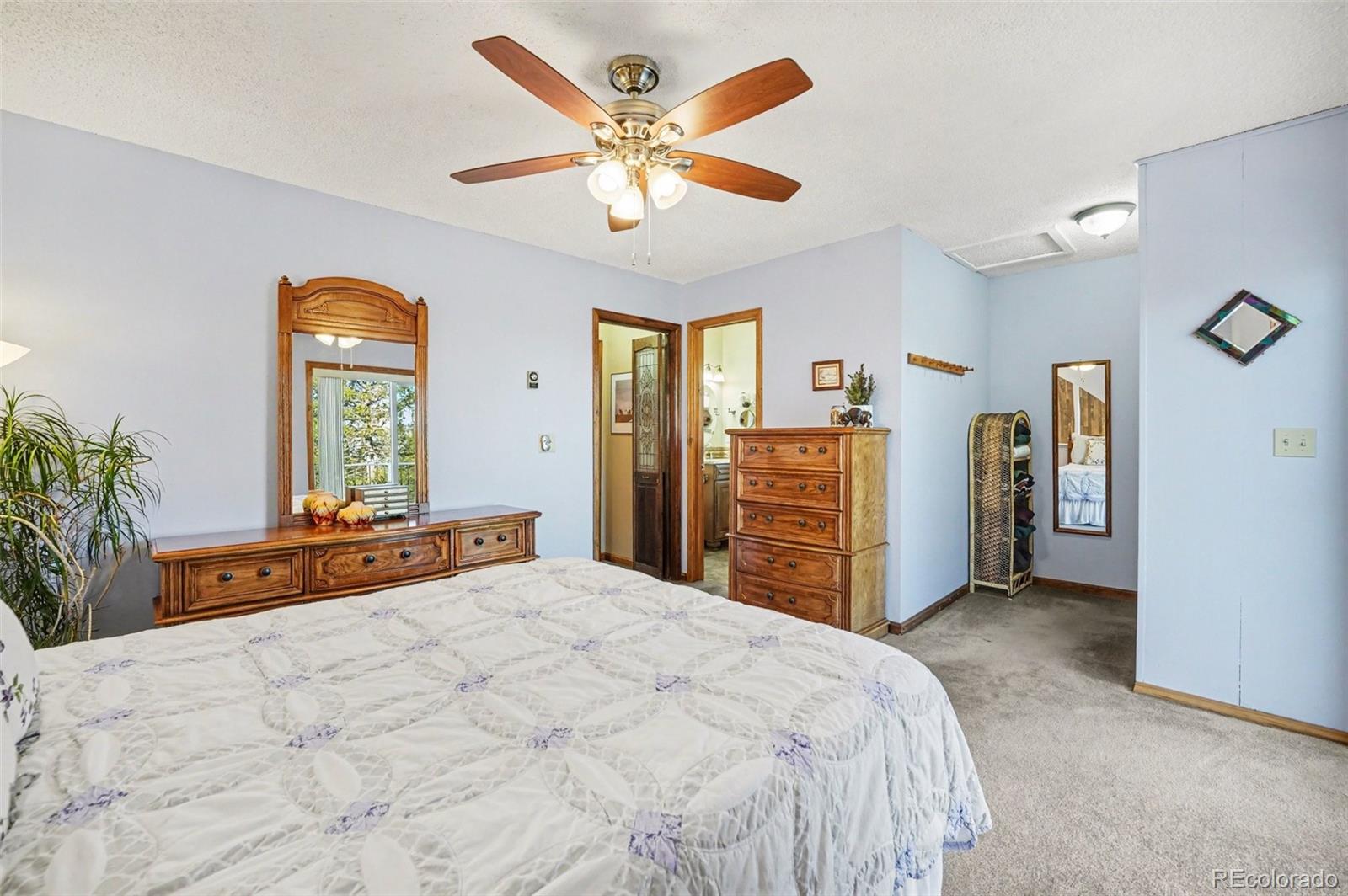 9780 South Warhawk Road Conifer, CO 80433 - Photo 18 of 44 a large bed sitting in a bedroom and chandelier