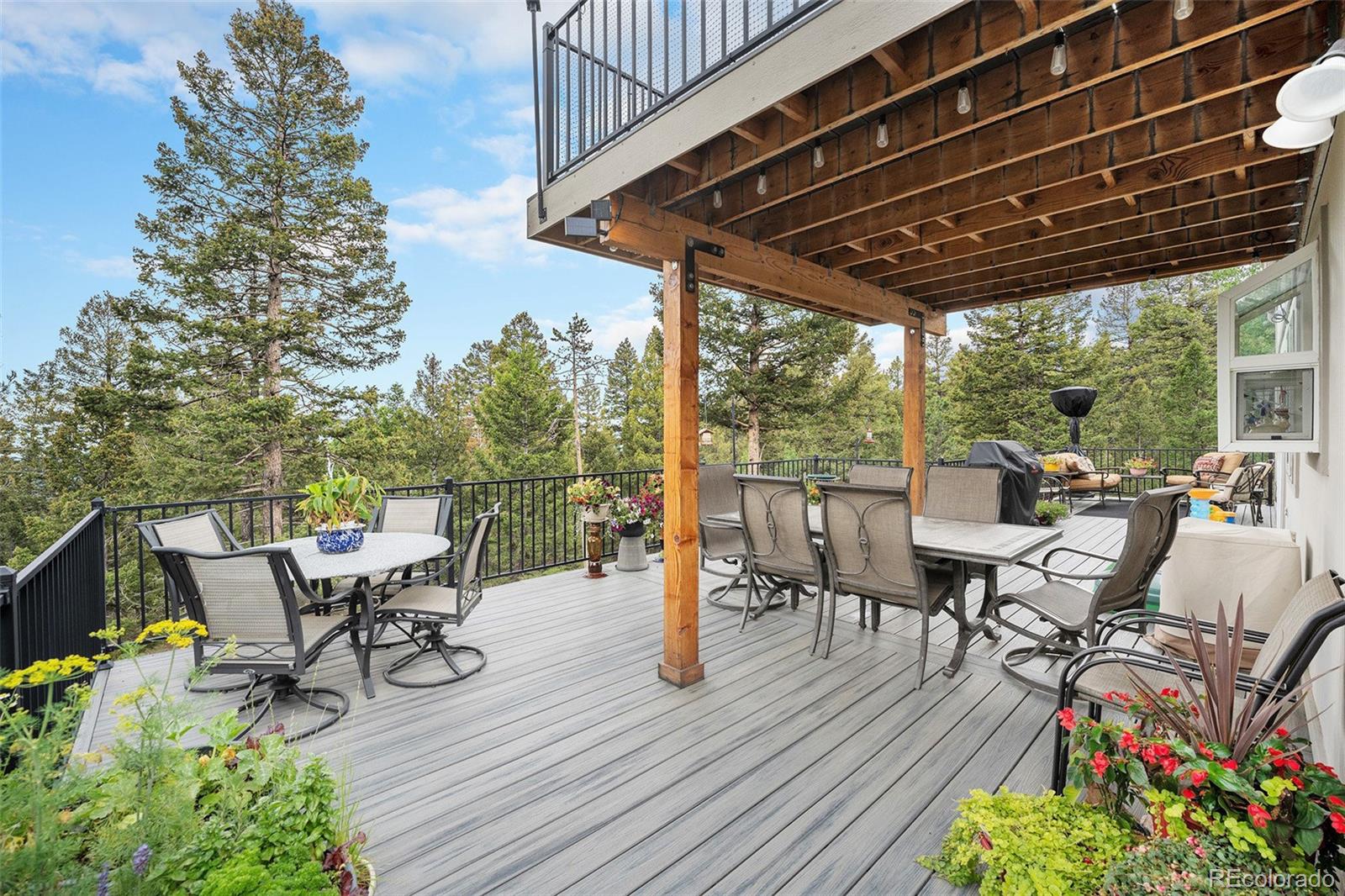 9780 South Warhawk Road Conifer, CO 80433 - Photo 33 of 44 a view of a patio with table and chairs potted plants with wooden floor and fence