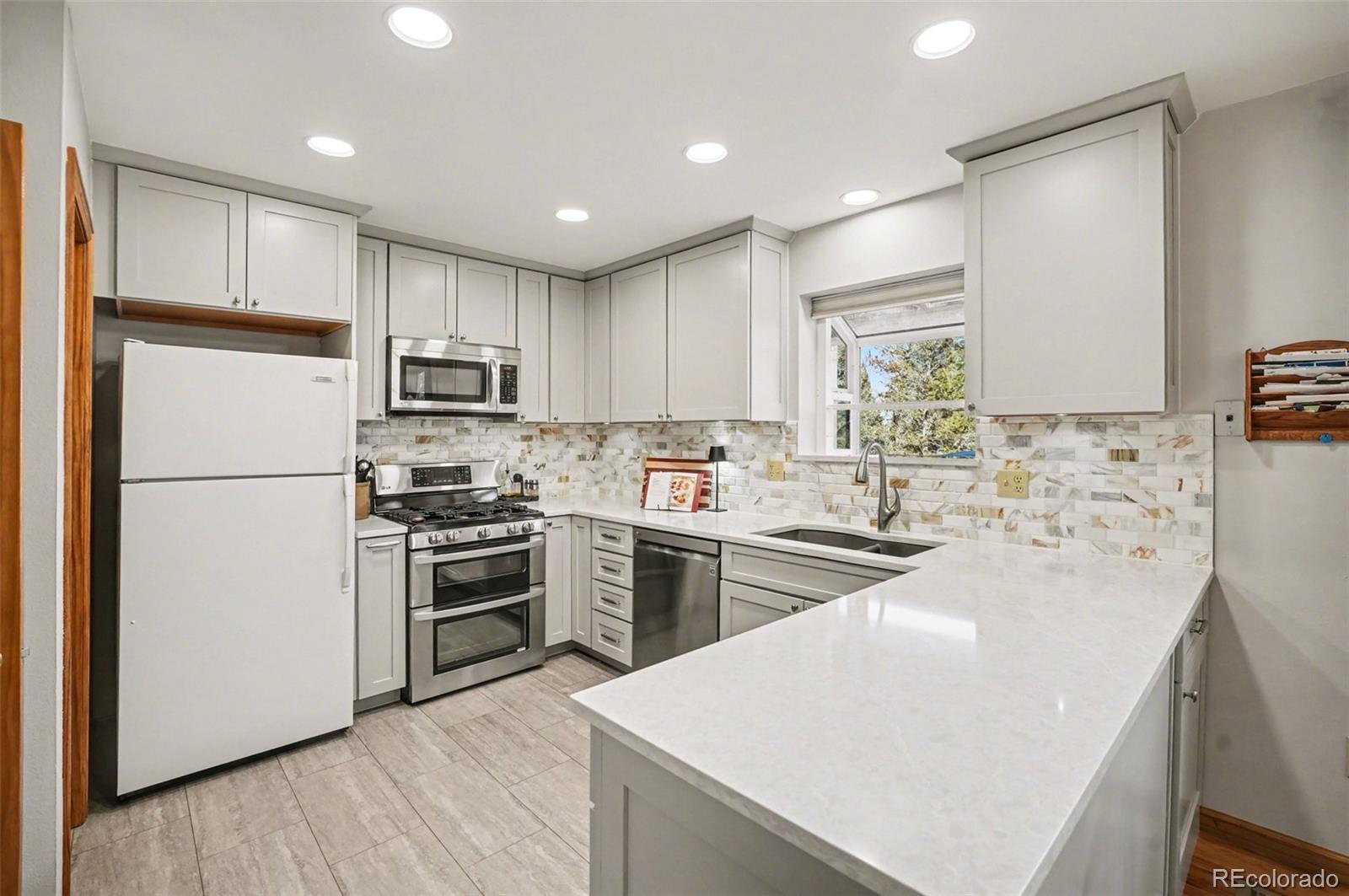 9780 South Warhawk Road Conifer, CO 80433 - Photo 4 of 44 a kitchen with kitchen island a sink a stove a refrigerator and cabinets