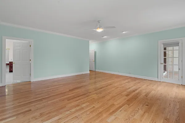 a view of an empty room with wooden floor and windows