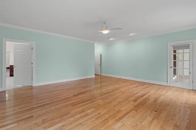 a view of an empty room with wooden floor and windows