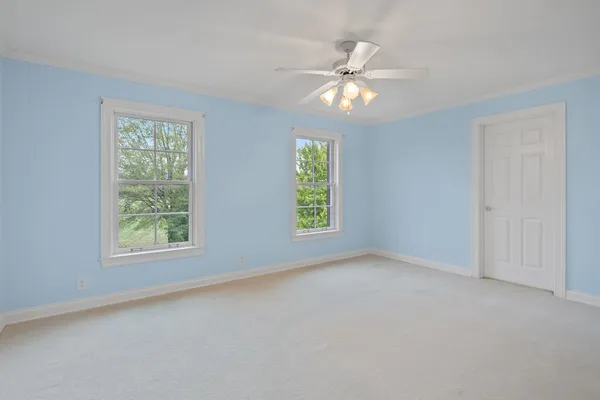 an empty room with windows and fan