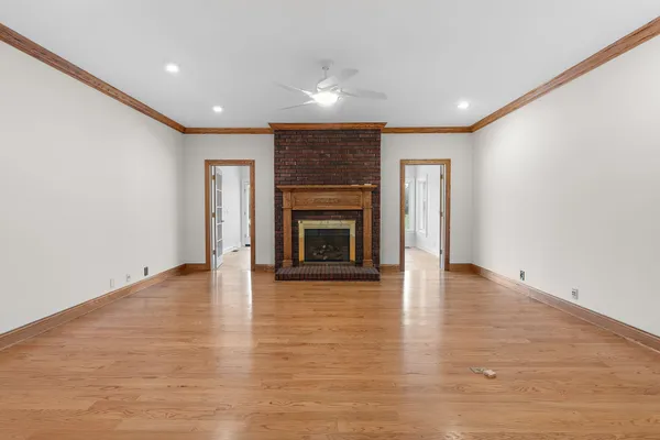 an empty room with wooden floor fireplace and windows