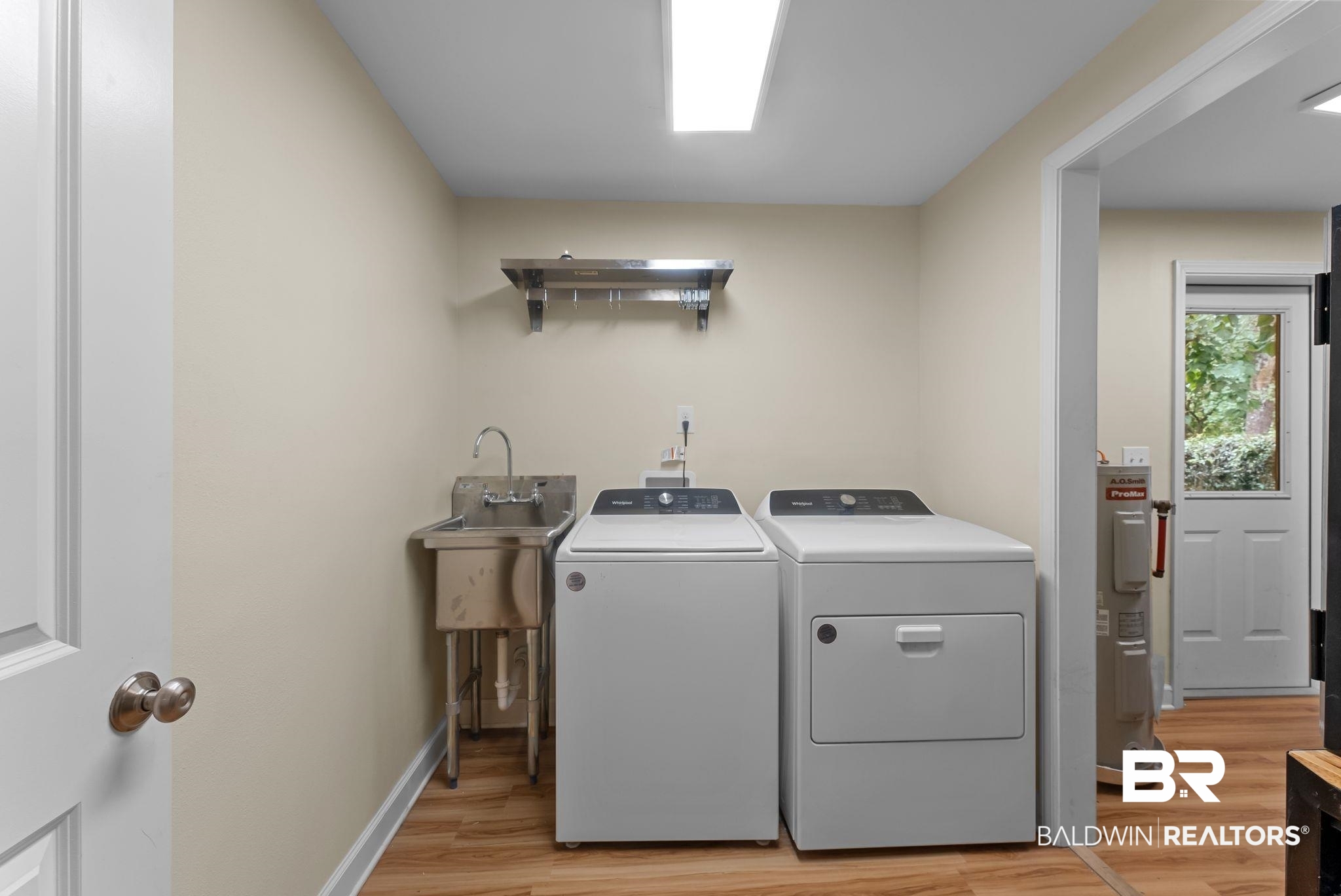 357 South School Street Fairhope, AL 36532 - Photo 31 of 44 Dedicated utility space featuring wood-finish flooring, a stainless steel utility sink, and a wall-mounted stainless steel shelf