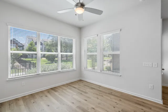 a view of an empty room with a window and wooden floor