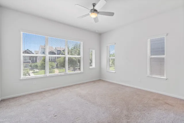 a view of empty room with windows and chandelier fan