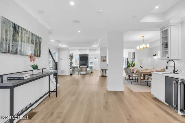 a kitchen with stainless steel appliances kitchen island granite countertop a stove a sink a refrigerator and white cabinets with wooden floor