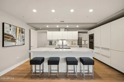 a kitchen with kitchen island granite countertop a sink and white cabinets with wooden floor