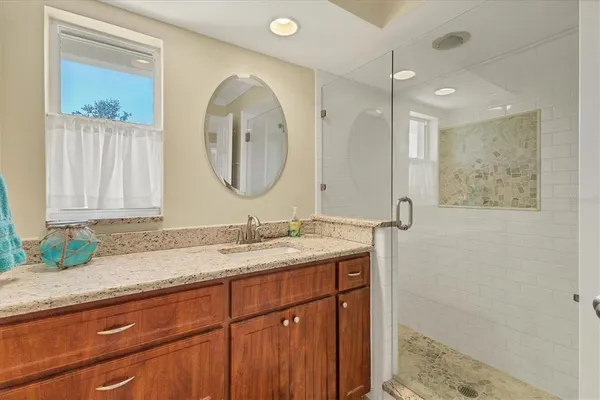 a bathroom with a granite countertop sink a mirror and a shower