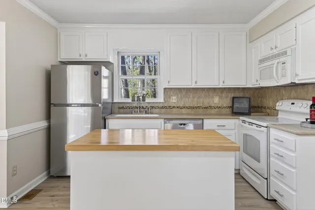 a kitchen with stainless steel appliances granite countertop a refrigerator sink stove and white cabinets