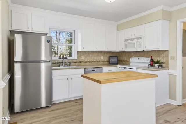 a kitchen with stainless steel appliances granite countertop a refrigerator sink and white cabinets