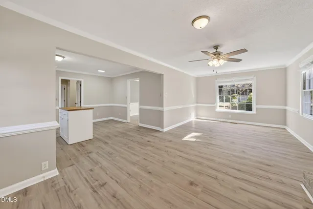 a view of an empty room with a window and wooden floor