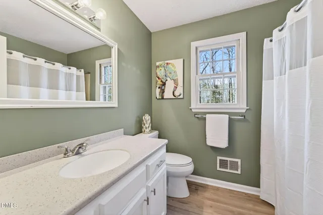 a bathroom with a granite countertop toilet sink and mirror