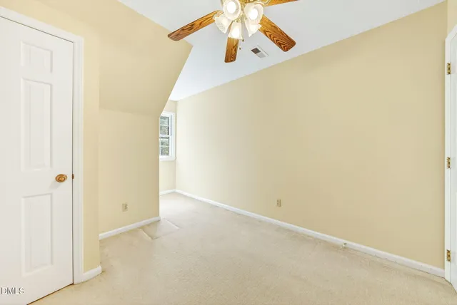 an empty room with a chandelier fan and windows