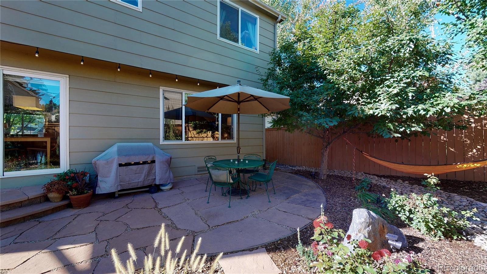 4841 Tarcoola Lane Highlands Ranch, CO 80130 - Photo 25 of 39 a view of a patio with table and chairs potted plants and large tree