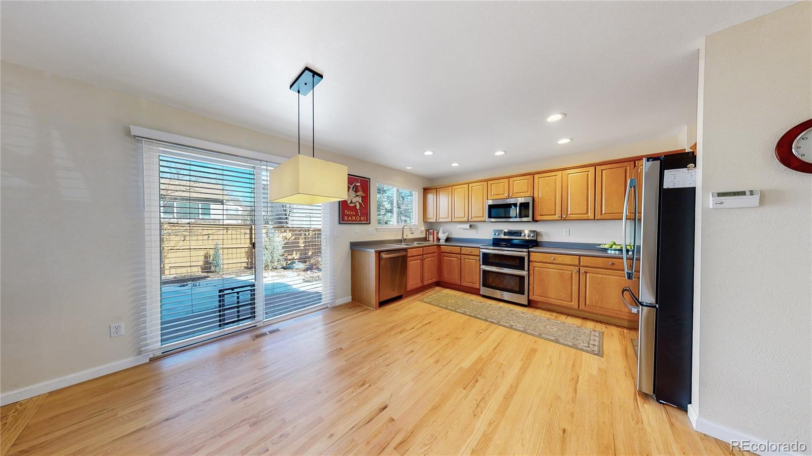 4841 Tarcoola Lane Highlands Ranch, CO 80130 - Photo 7 of 39 a kitchen with stainless steel appliances granite countertop a refrigerator a stove top oven a sink dishwasher and wooden cabinets with wooden floor