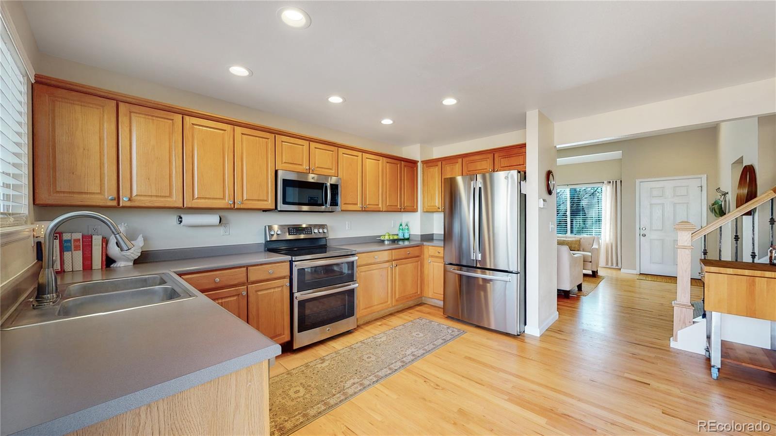 4841 Tarcoola Lane Highlands Ranch, CO 80130 - Photo 8 of 39 a kitchen with stainless steel appliances granite countertop a refrigerator stove top oven and sink