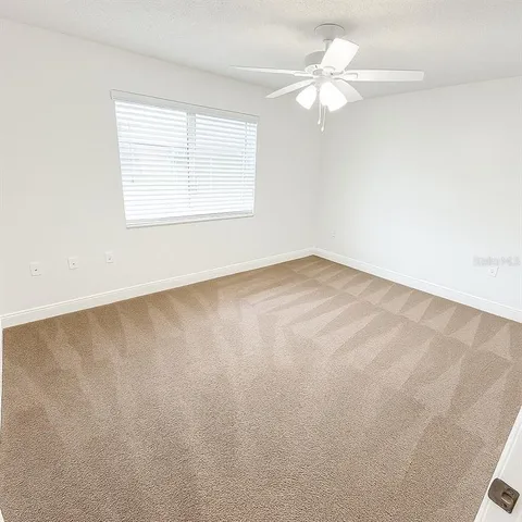 an empty room with a window and a ceiling fan