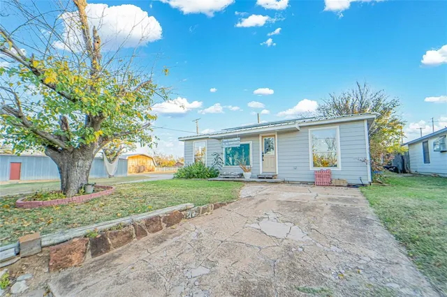 a front view of a house with a garden and trees