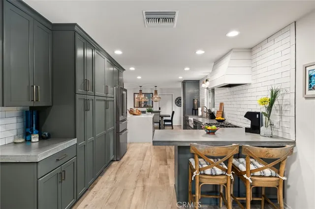 a kitchen with stainless steel appliances granite countertop dining table chairs refrigerator and sink