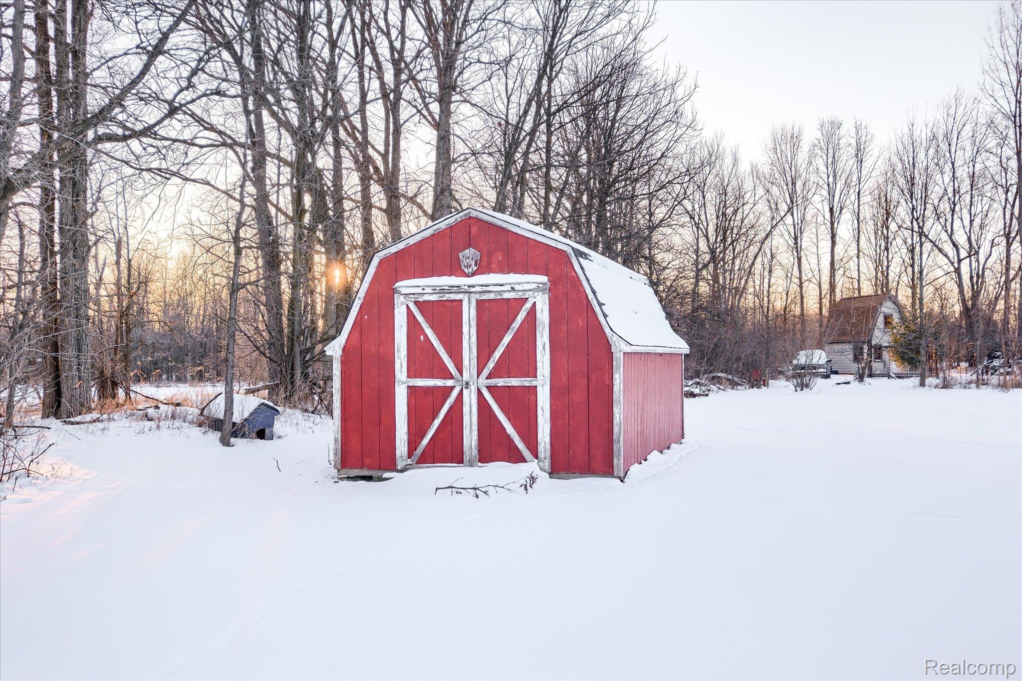 6941 North Lake Pleasant Road North Branch, MI 48461 - Photo 44 of 51 Snow covered structure featuring a storage shed and view of scattered trees
