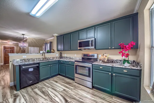 a kitchen with granite countertop a sink cabinets and stainless steel appliances