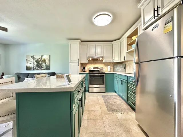 a kitchen with kitchen island a refrigerator a sink a stove and a refrigerator