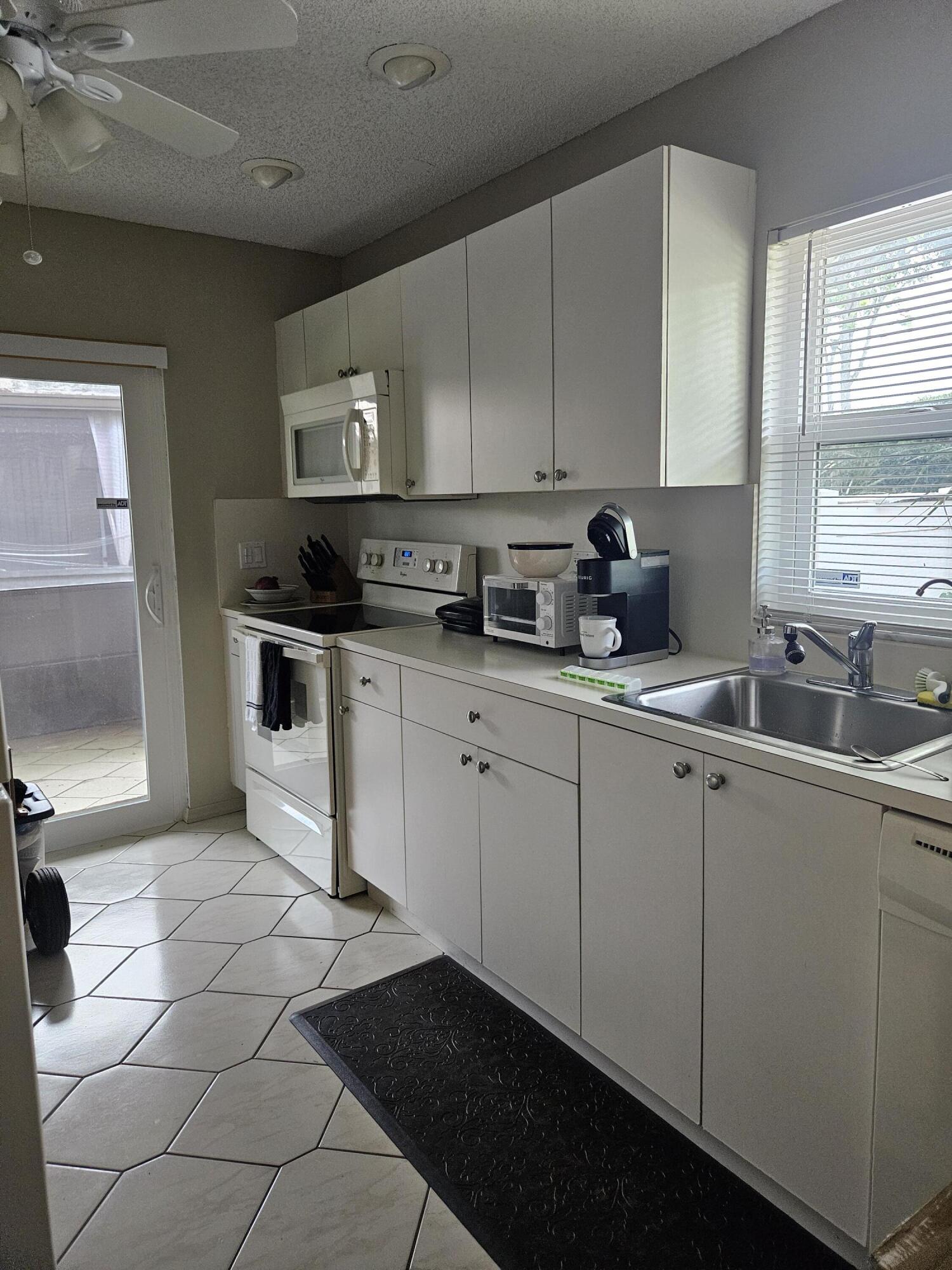 8977 Echo Lane, Unit D Boca Raton, FL 33496 - Photo 7 of 13 a kitchen with stainless steel appliances a sink a stove a microwave a sink and cabinets