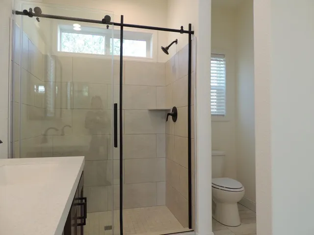 a bathroom with a granite countertop shower a toilet and a sink