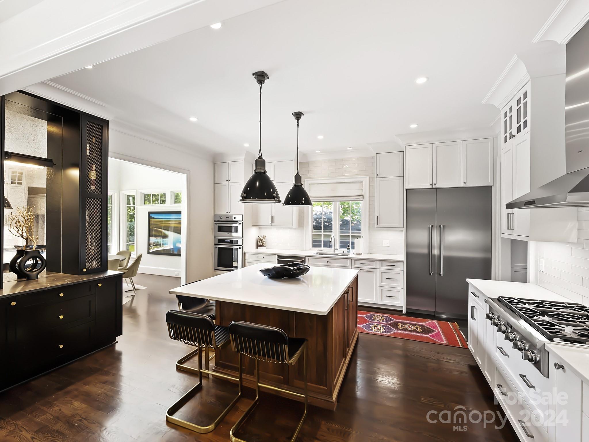 1621 Sterling Road Charlotte, NC 28209 - Photo 12 of 48 a kitchen with stainless steel appliances kitchen island granite countertop a stove a refrigerator a sink a dining table and chairs with wooden floor