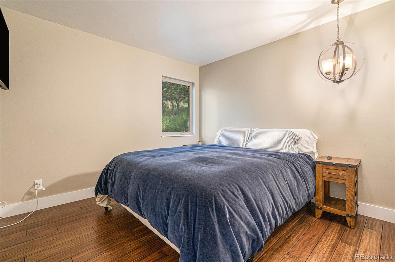 4650 Forest Hill Road Evergreen, CO 80439 - Photo 16 of 36 a bedroom with a bed and wooden floor