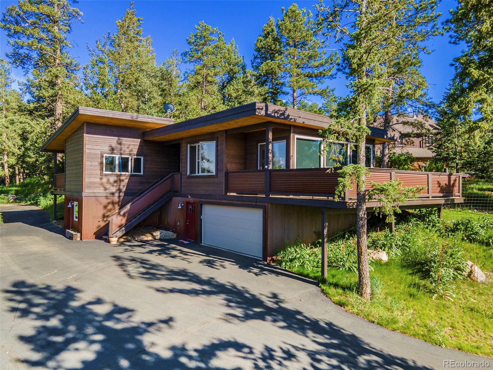 4650 Forest Hill Road Evergreen, CO 80439 - Photo 2 of 36 a front view of a house with a garden