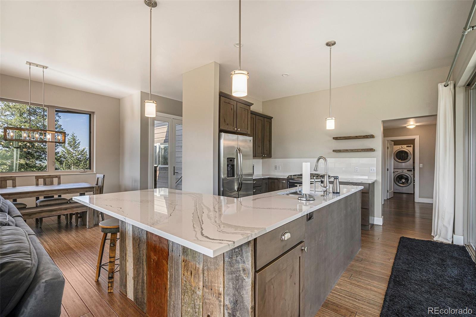 4650 Forest Hill Road Evergreen, CO 80439 - Photo 9 of 36 a kitchen with stainless steel appliances kitchen island a large island in the center and wooden floor