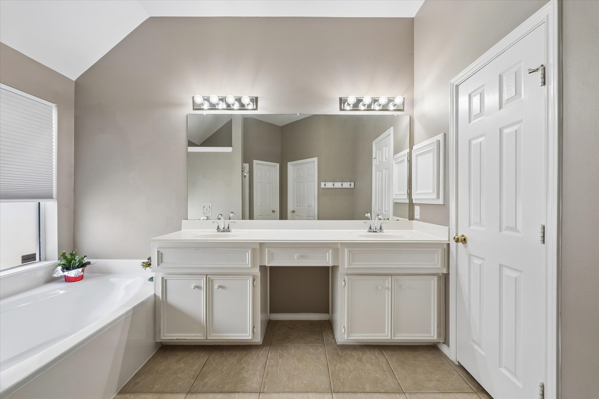 3118 Valley Court Manvel, TX 77578 - Photo 15 of 38 This bathroom features a double vanity with ample storage, modern lighting, and a large mirror. It includes a spacious bathtub and has a clean, neutral color palette, creating a relaxing atmosphere.