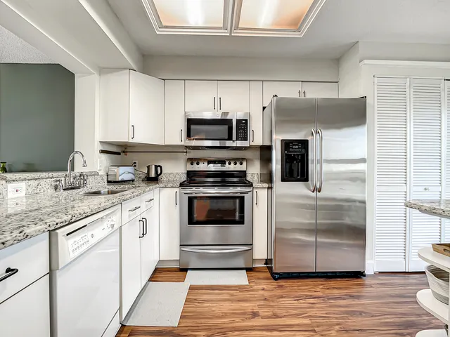 a kitchen with granite countertop a refrigerator stove and microwave