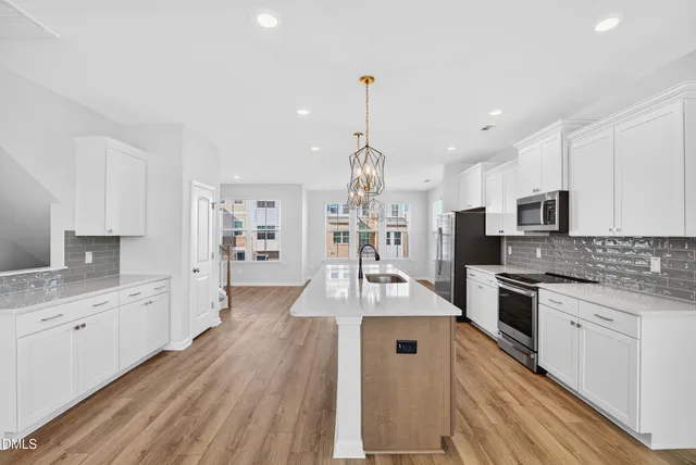 a large kitchen with granite countertop a large counter top a sink stainless steel appliances and cabinets