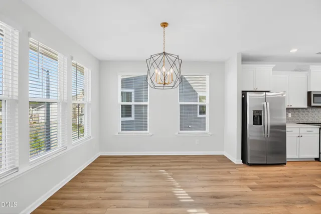 a view of an empty room with window and wooden floor