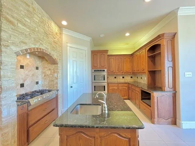 a kitchen with stainless steel appliances granite countertop a sink a stove and a refrigerator