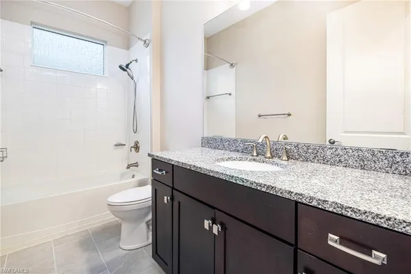 a bathroom with a granite countertop sink a toilet and shower