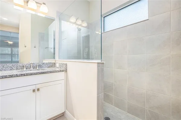 a bathroom with a granite countertop shower sink and mirror