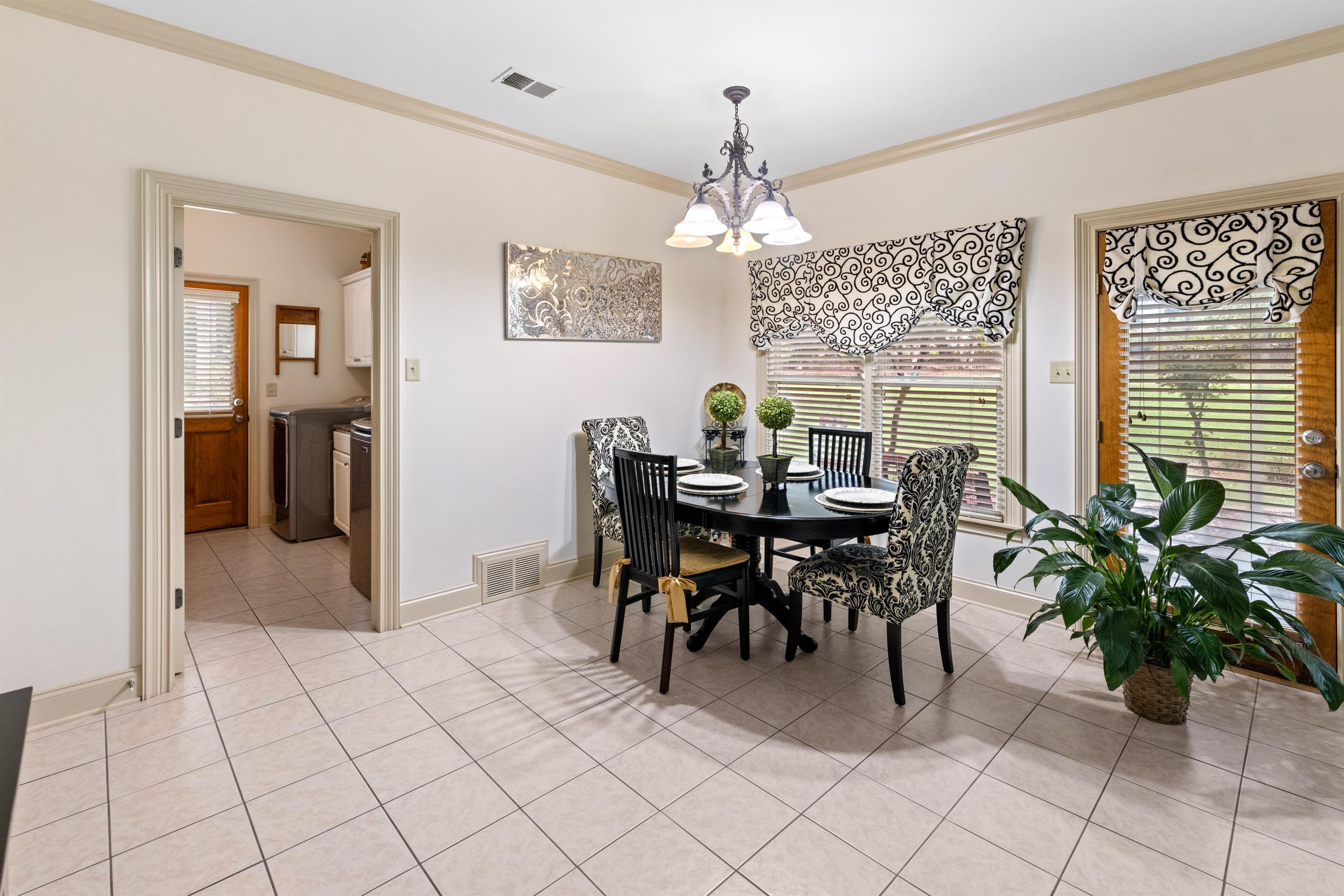 11241 Latting Road Eads, TN 38028 - Photo 11 of 31 Tiled dining space featuring a notable chandelier, crown molding, and washing machine and clothes dryer